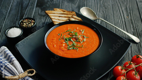 Fotografie From above view of tomato soup in black bowl sprinkled with herb served with cri