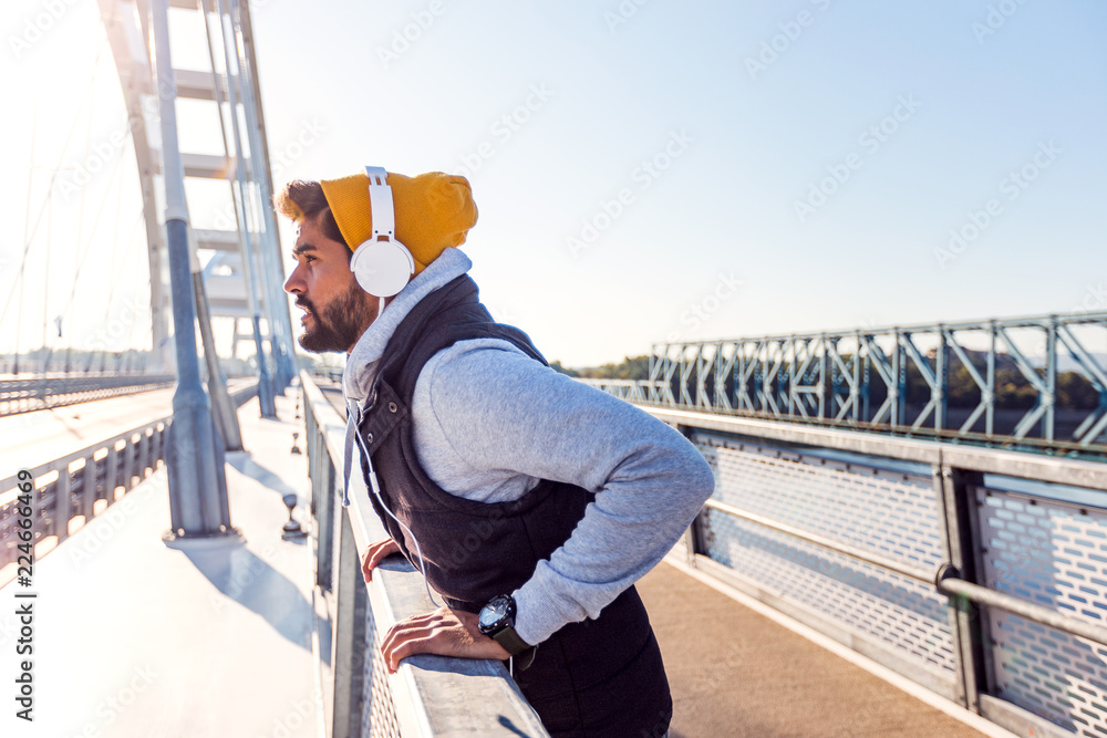 Young fit man preparing for training on the bridge