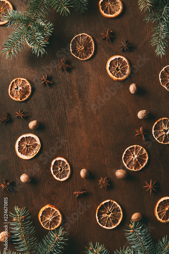 top view of dried orange slices, anise stars and nutmeg seeds on wooden background with pine branches for christmas