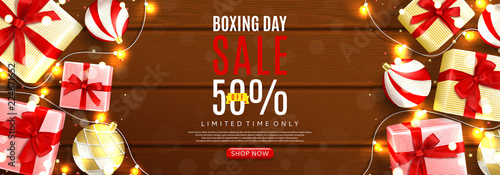 Boxing day sale web banner. Top view on realistic gift boxes and Christmas balls on rustic wooden texture. Vector illustration with confetti and effect bokeh.