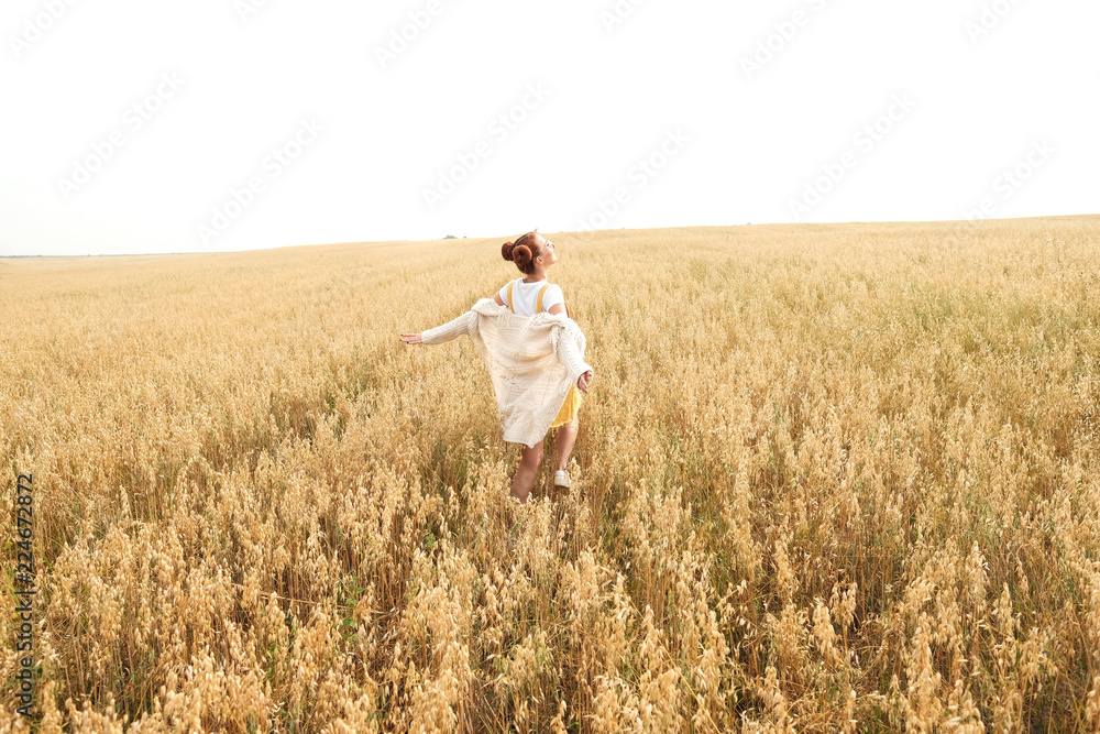 girl with red hair in the autumn field of wheat
