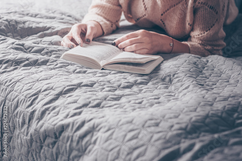 Girl reading a book on grey cozy bed. Home Concepts. Place for text