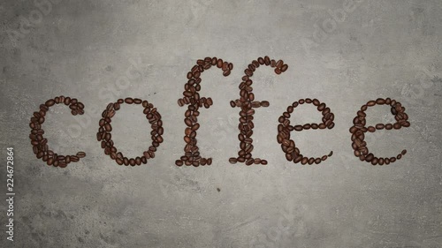 Hands full of brown coffee beans. 
The coffee beans contain a coffee inscription. Top view on food ingredients, stop motion.