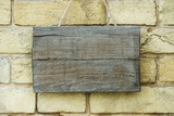 empty wooden board hanging on brick wall