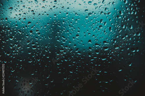 Raindrop on glass window  blue drops.