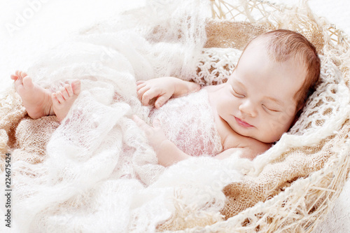 Beautiful little newborn boy 3 weeks sleeps in a basket with knitted plaid. Portrait of pretty smiling newborn boy