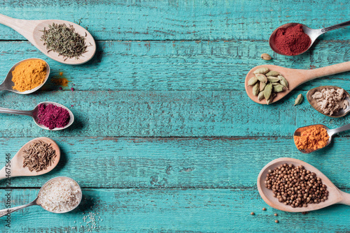 Fototapeta Naklejka Na Ścianę i Meble -  top view of spoons with various dried seasonings on turquoise wooden surface