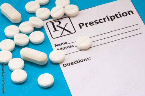 Clean recipe for prescription drug statement is near scattered white pills and tablets on a blue background. Pharmacological or medical concept photo to refer to prescription medicines for patients