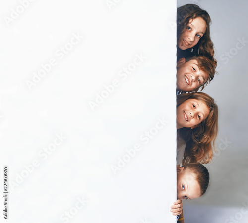 a Four children holding a big billboard, appear from the side of the billboard.