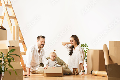 Couple moving to a new home. Happy married people with newborn child buy a new apartment to start life together. The family at repair and relocation planing to accommodation against boxes