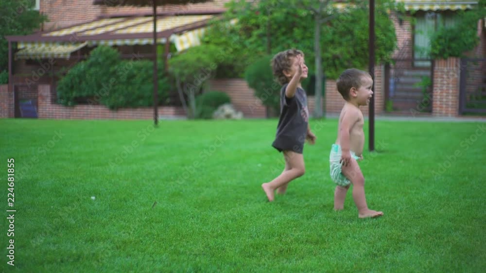 Two little brothers playing with blonde hair and blue eyes, running and laughting in the garden Two little brothers playing with blonde hair and blue eyes, running and laughting in the garden
