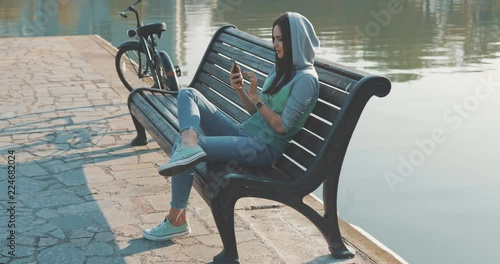 Wallpaper Mural Brunette hipster woman wearing in hoodie selfie in park . Caucasian girl having fun with mobile phone , texting sending and reading messages , making photos . 4K video shooting by handheld gimbal Torontodigital.ca