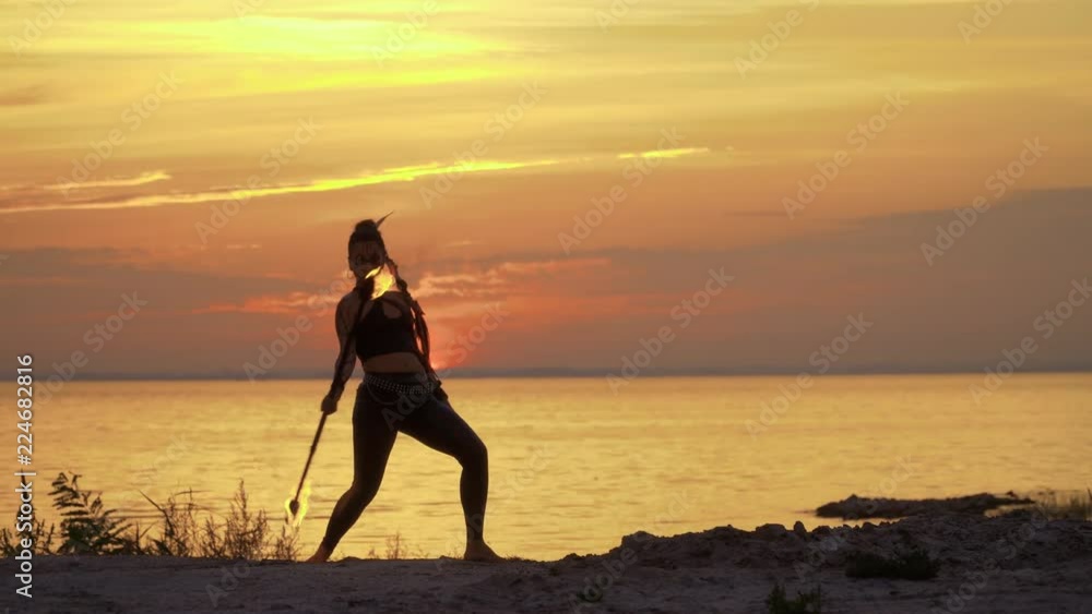 Wild looking woman makes fires show on sunset Wild looking woman makes fires show on sunset