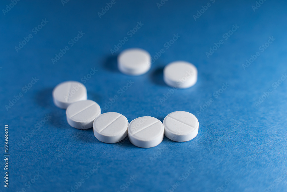 Happy smile made from white pills on blue background Happy smile made from white pills on blue background
