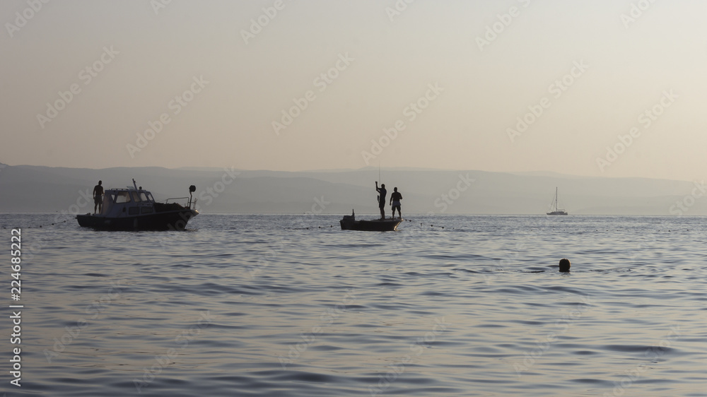 Silhouette of fishermen on ships at sea