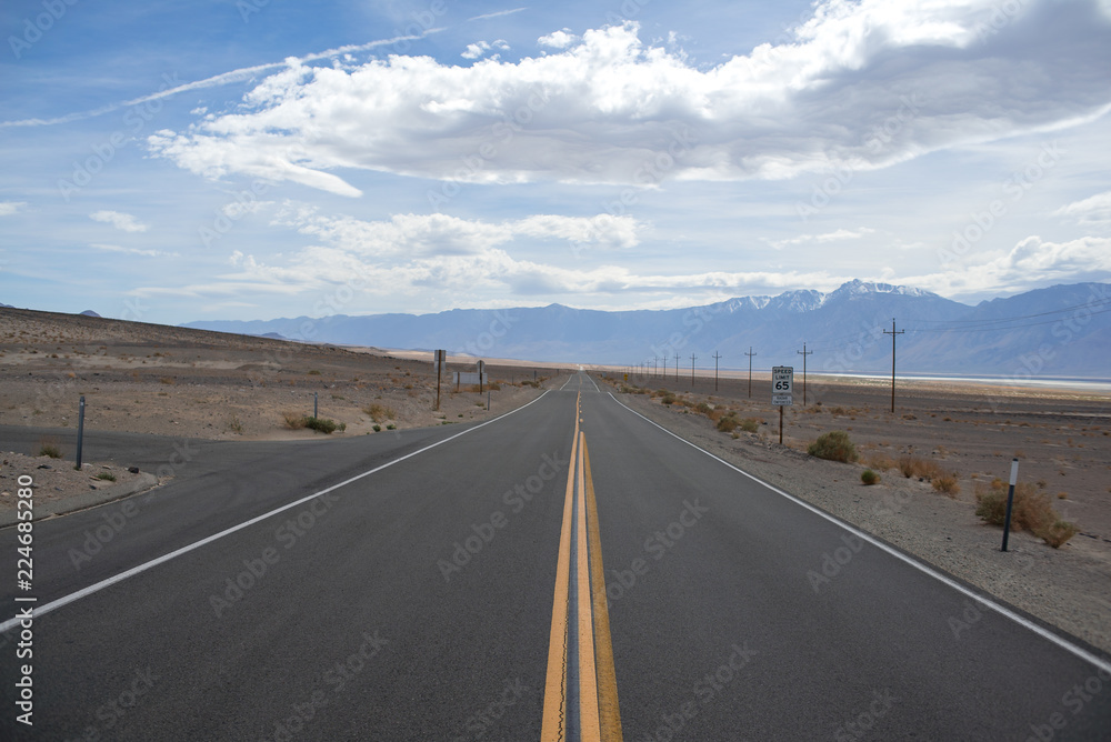 Straight asphalt road in desert with power pillars and mountains Straight asphalt road in desert with power pillars and mountains