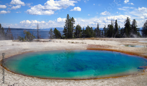turquoise colored hot pool in Yellowstone National Park, yellowstone lake in background (Wyoming , USA) 