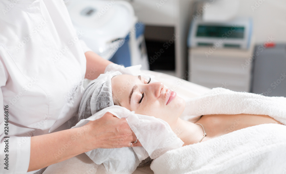 Wipe with sterile napkin face. Young pretty woman receiving treatments in beauty salons. Facial cleansing foam using. Wipe with sterile napkin face. Young pretty woman receiving treatments in beauty salons. Facial cleansing foam using.