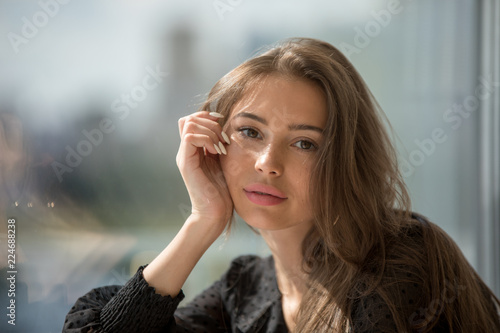 Portrait of an attractive girl on a window background.