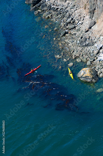 Bright kayakers and a stone