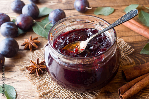 Plum jam in a glass jar. Fresh plum fruit on a wooden table. photo