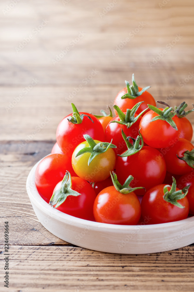 Cherry tomatoes red in ceramic bowl on wooden background Cherry tomatoes red in ceramic bowl on wooden background