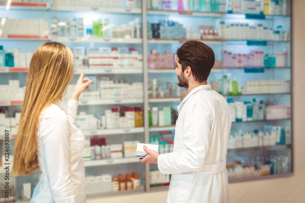 Experienced pharmacist counseling female customer in modern pharmacy
