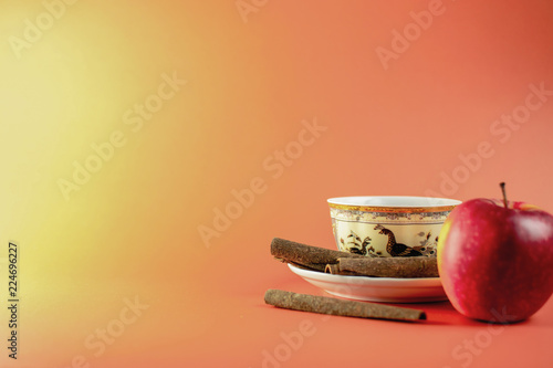 Apple and cup of tea with cinnamon on orange background, banner template
