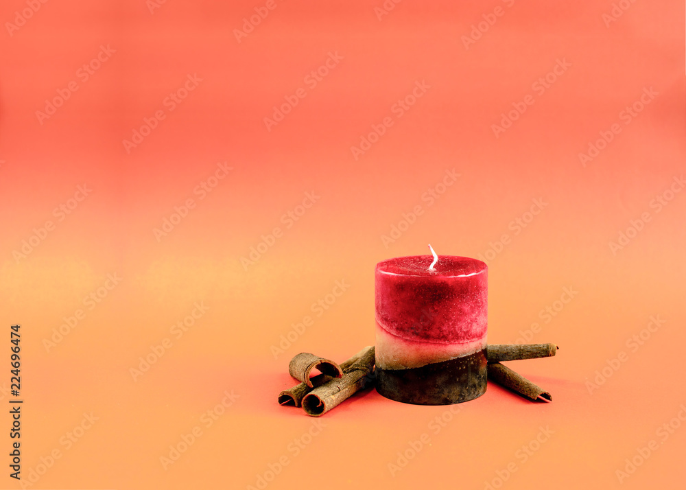 Red and brown candle with cinnamon on a orange autumn background - obrazy, fototapety, plakaty 