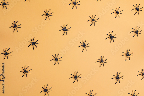 Halloween background with decorative spiders on orange backdrop.