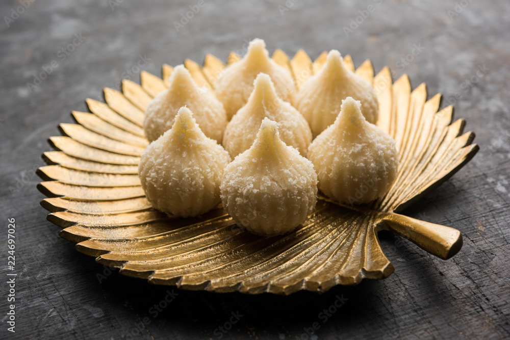 Sweet Modak made using coconut, khoya and sugar. Popular Maharashtrian recipe offered to lord Ganesha in Ganesh Festival. Served in a plate. Selective focus