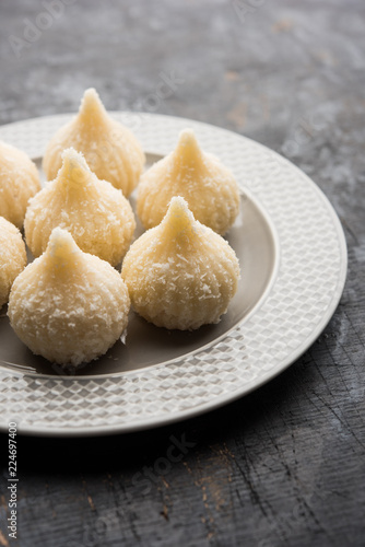 Sweet Modak made using coconut, khoya and sugar. Popular Maharashtrian recipe offered to lord Ganesha in Ganesh Festival. Served in a plate. Selective focus photo