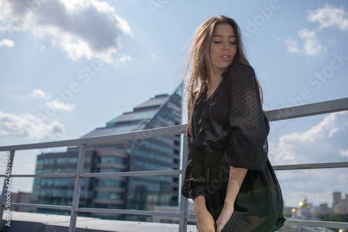 Young woman standing on the terrace overlooking the city. © kanashkin