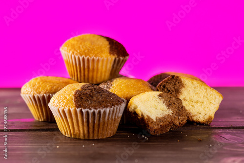 Group of four whole two halves of fresh baked marble muffin with pink in background