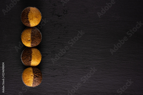Group of four whole fresh baked marble muffin flatlay on grey stone photo