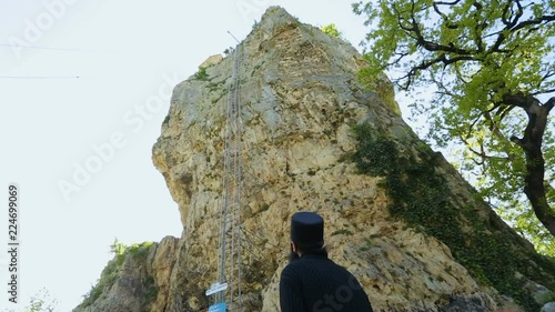 Monk observing Katskhi Pillar with ancient church on top in Chiatura, Georgia