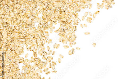 Lot of whole flat raw rolled oats left upper corner isolated on white background
