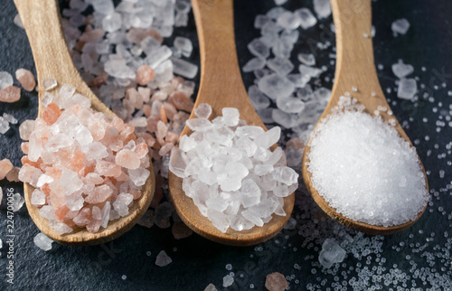Different types of salt. Top view on three wooden spoons