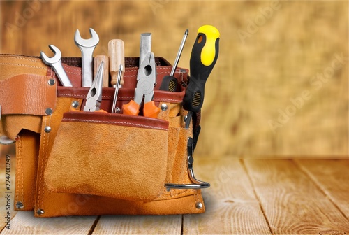 Tool belt with tools on wooden background photo