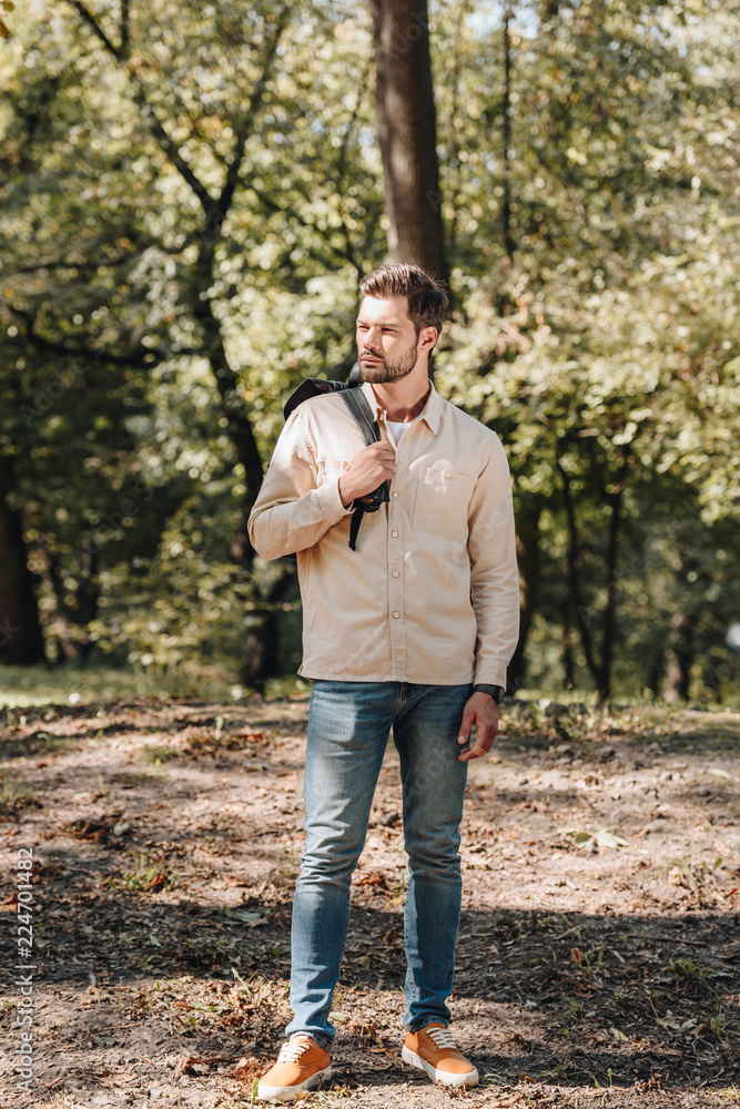 stylish young man with backpack standing in autumn park stylish young man with backpack standing in autumn park