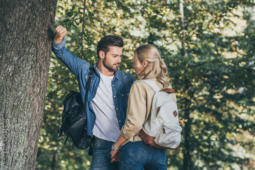 young couple with backpacks looking at each other in park
