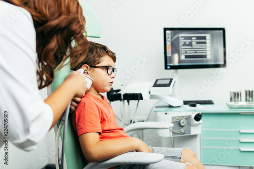 Young boy at medical examination or checkup in otolaryngologist's office. Ear irrigation and earwax removal.