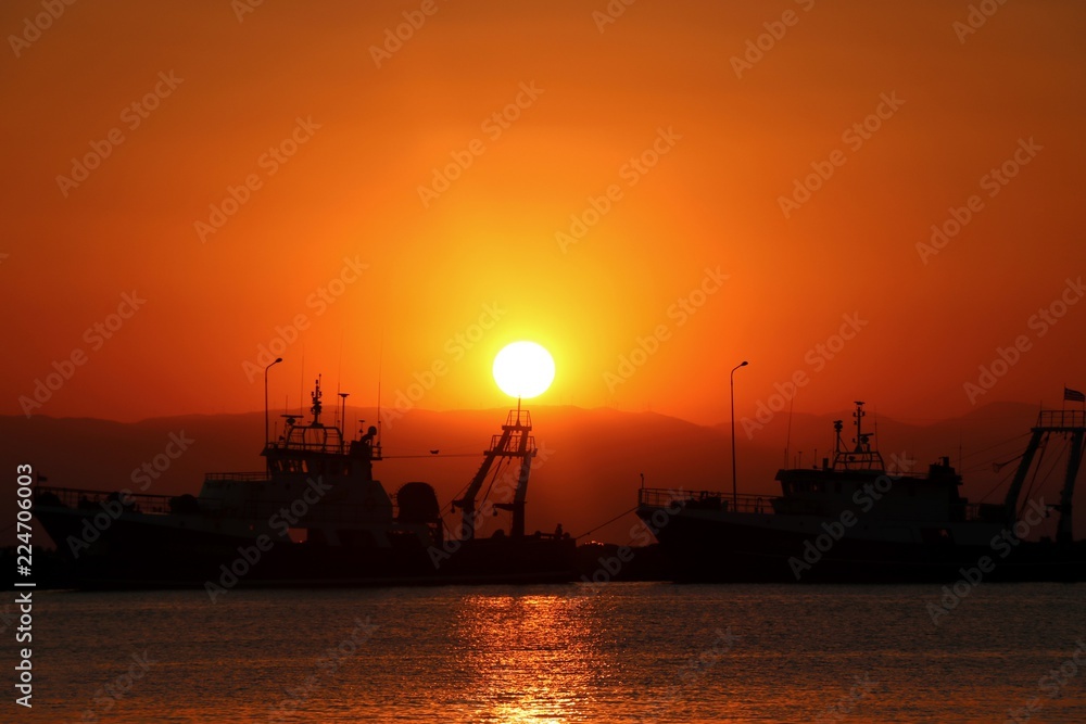 Sunset in the port, golden sea. Ships in the harbour. 