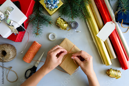 Woman's hands decorate present box on gray wooden background. New Year and Christmas decorations concept.