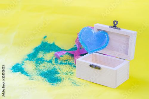 blue heart on gift box wooden and yellow paper background,
