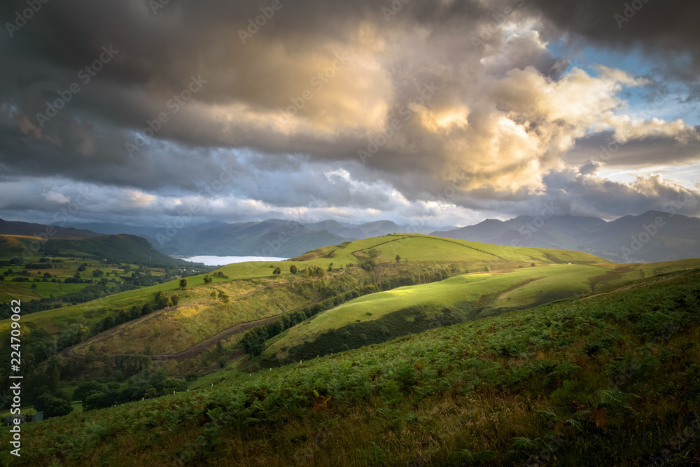 Beautiful big orange yellow cloud over green and sun lit landscape of England Lake District near Keswick Beautiful big orange yellow cloud over green and sun lit landscape of England Lake District near Keswick
