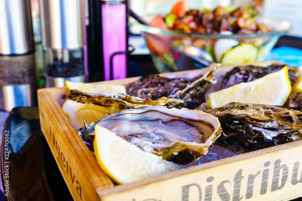 Fresh oysters on ice with lemon wedges.