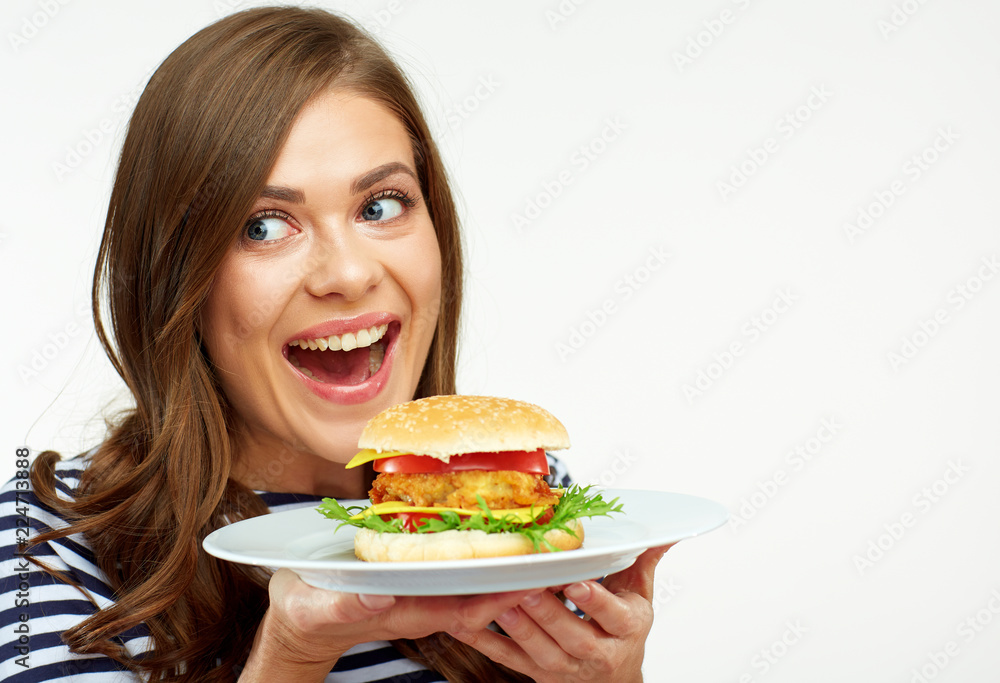 Happy emotional woman holding burger on white plate.