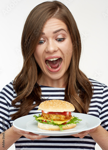 Happy emotional woman holding burger on white plate.