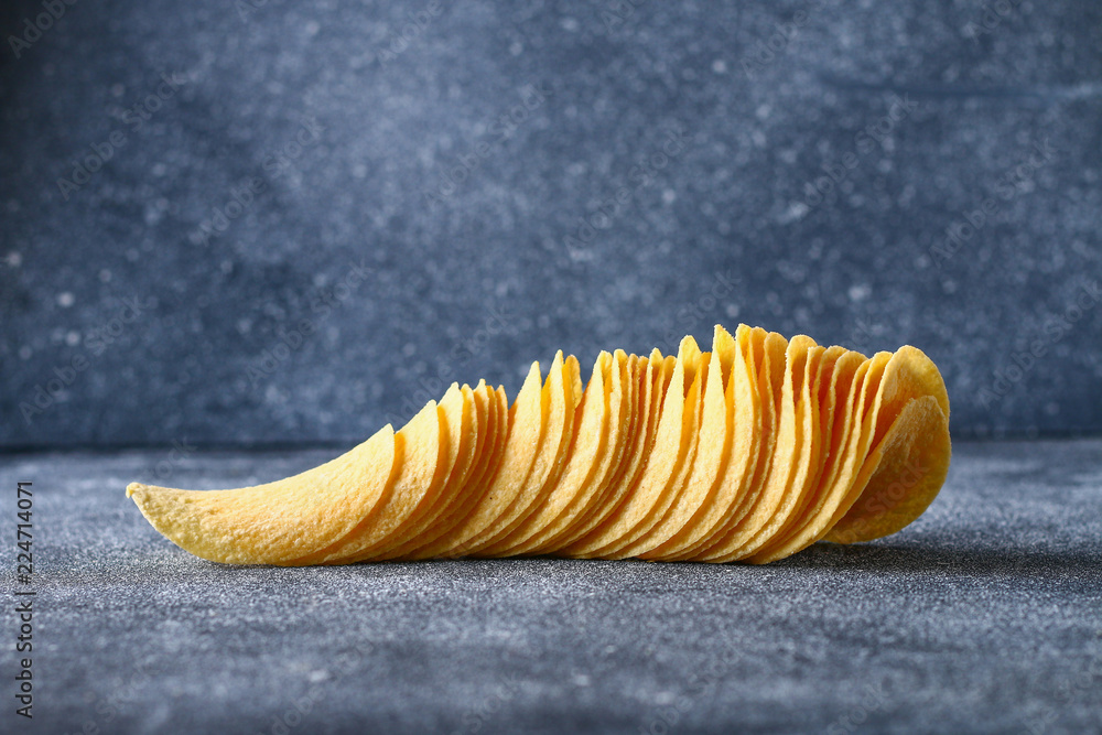 Naklejka premium A stack of crispy chips on a gray dark table. Snack.